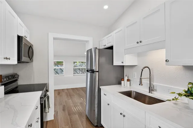 a kitchen with stainless steel appliances granite countertop a refrigerator sink and wooden cabinets