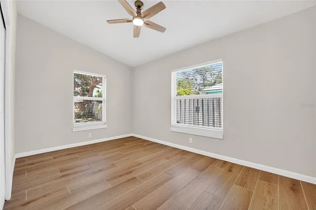 a view of an empty room with wooden floor and a window
