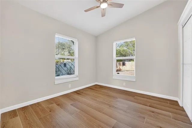 a view of an empty room with wooden floor and a window