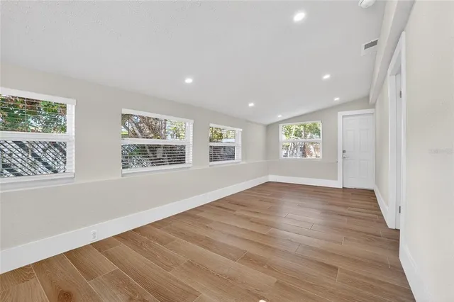 an empty room with wooden floor and windows
