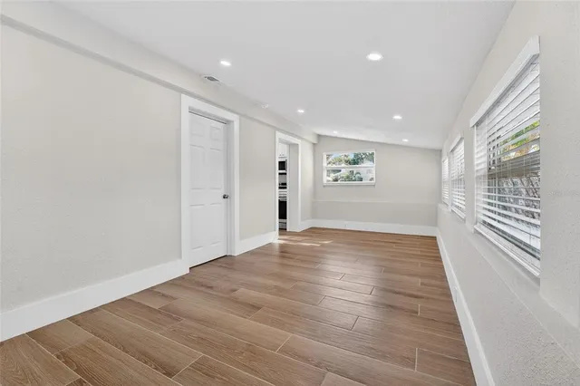 a view of empty room with wooden floor and fan