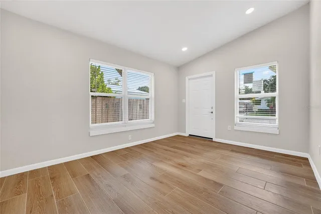 a view of an empty room with wooden floor and a window