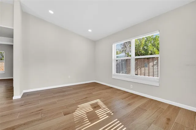 a view of an empty room with wooden floor and a window