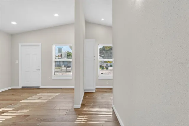 a view of a hallway with wooden floor and a living room