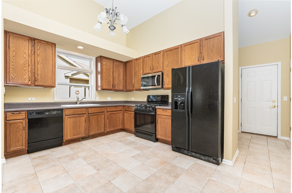 611 Chestnut Drive Oswego, IL 60543 - Photo 3 of 15 a kitchen with a refrigerator sink and wooden cabinets