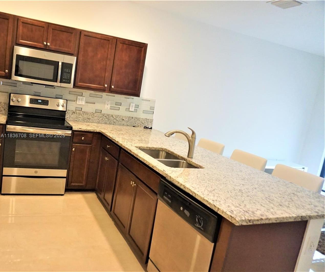 10498 West 33rd Way Hialeah, FL 33018 - Photo 15 of 28 a kitchen with stainless steel appliances granite countertop a sink stove and microwave