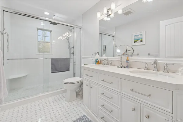 a bathroom with a toilet a sink a mirror and a shower