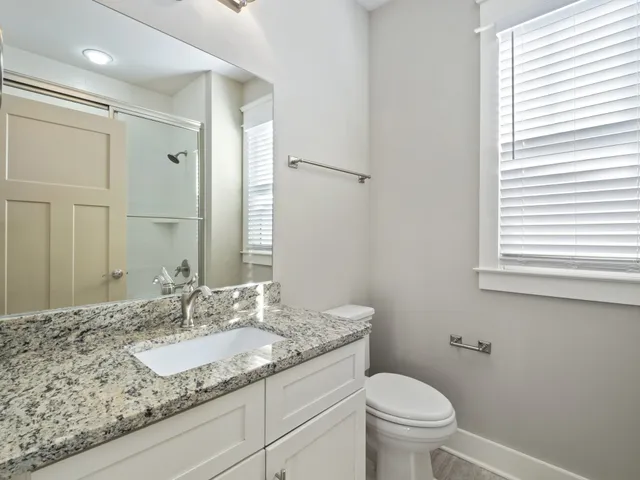 a bathroom with a granite countertop sink toilet and a mirror