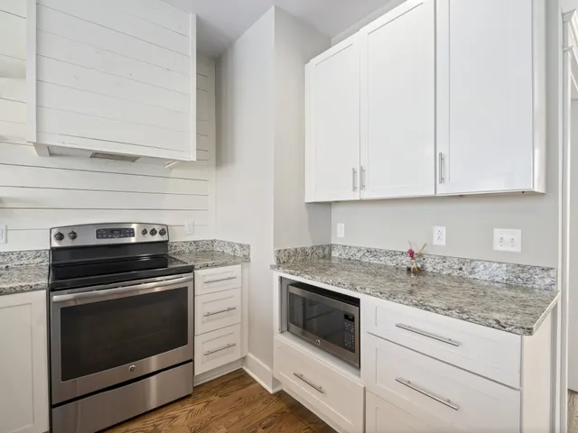 a kitchen with granite countertop white cabinets and white appliances
