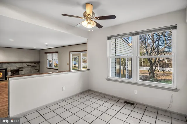 an empty room with wooden floor fire place and windows