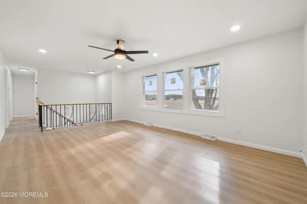 a view of empty room with wooden floor and fan