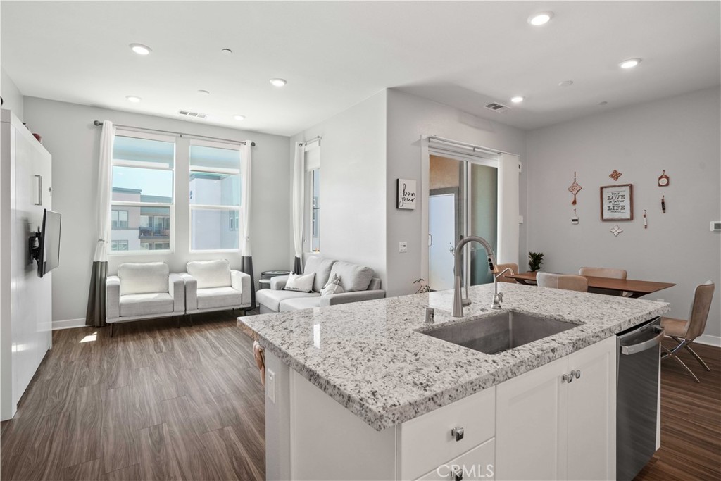 a view of kitchen island a sink wooden floor and a granite counter top