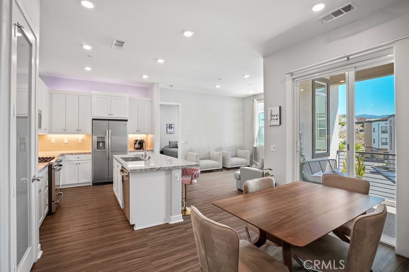 26973 West Prospector Road, Unit 302 Valencia, CA 91381 - Photo 7 of 22 a open dining room with stainless steel appliances granite countertop furniture wooden floor and a kitchen view