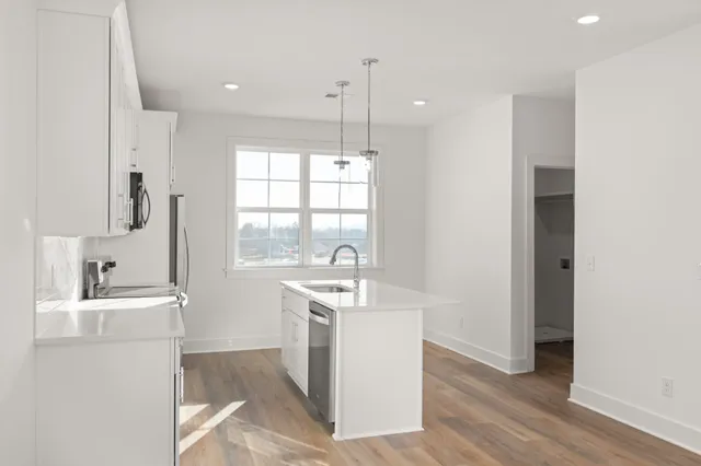 a room with kitchen island stainless steel appliances a stove a sink and a window