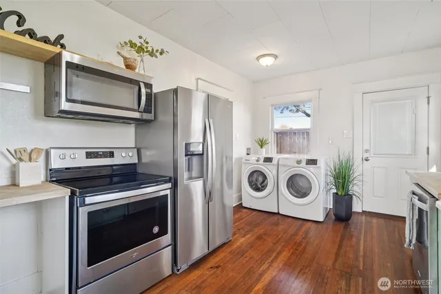 a kitchen with a stove a washer and dryer with wooden floor