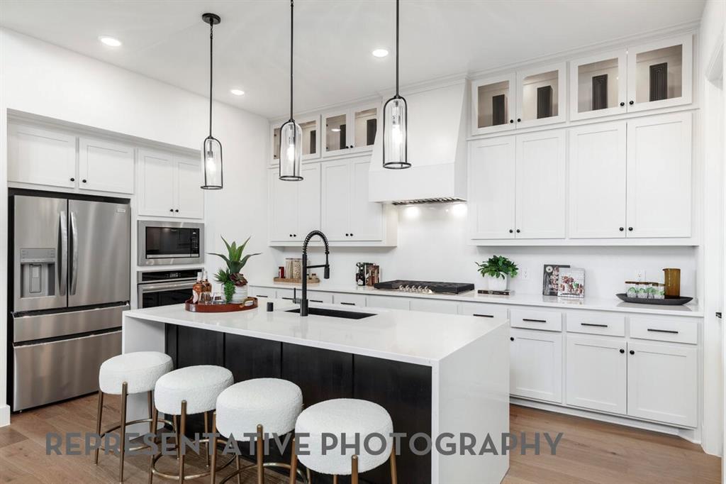 4415 Azalea Trail Oak Point, TX 75068 - Photo 4 of 38 a kitchen with stainless steel appliances granite countertop a sink a stove a refrigerator and white cabinets with wooden floors