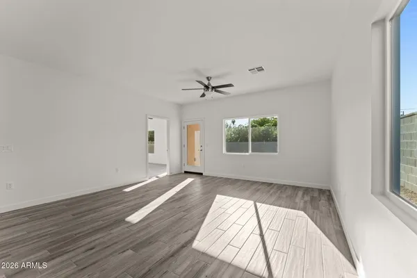 an empty room with wooden floor a ceiling fan and windows