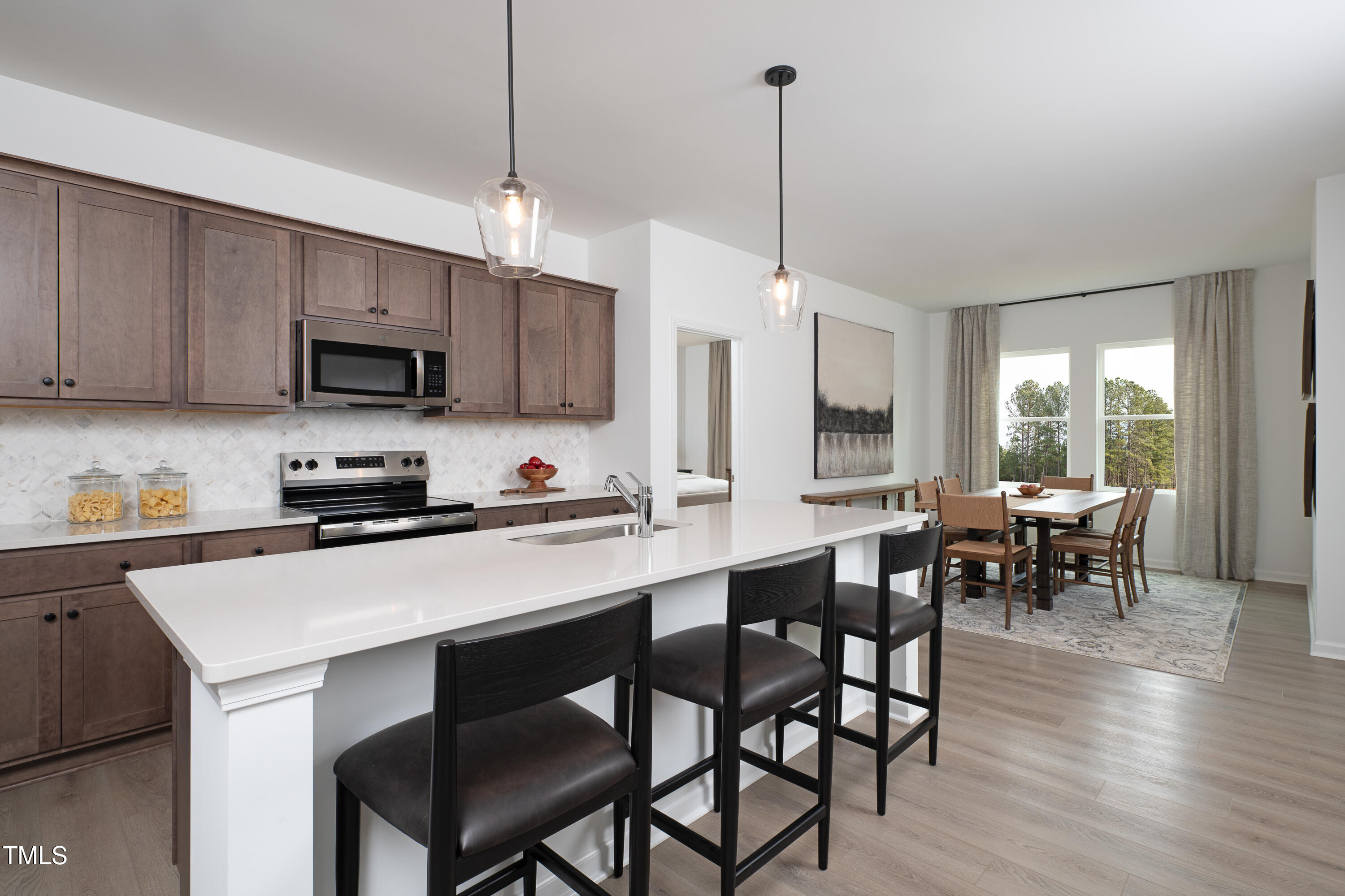 11751 Salers Loop Middlesex, NC 27557 - Photo 4 of 30 a kitchen with stainless steel appliances granite countertop a stove a refrigerator a kitchen island a dining table and chairs with wooden floor