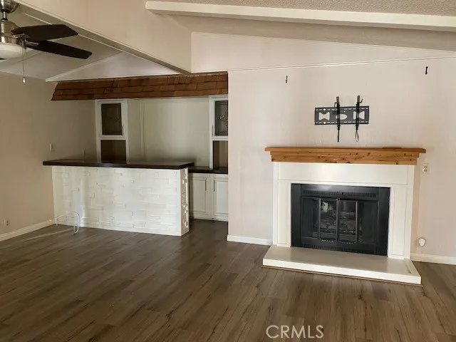 a view of an empty room with wooden floor and a fireplace