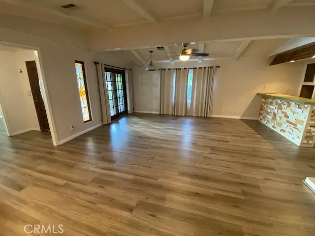 a view of an empty room with wooden floor and a fireplace