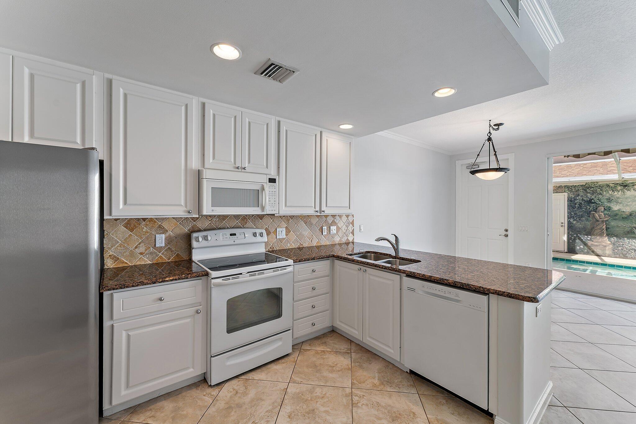 148 Middlebury Drive Jupiter, FL 33458 - Photo 10 of 32 a kitchen with white cabinets stainless steel appliances and sink