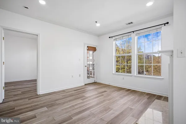 an empty room with windows a fireplace and wooden floor