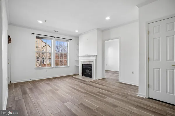a view of empty room with wooden floor and fireplace
