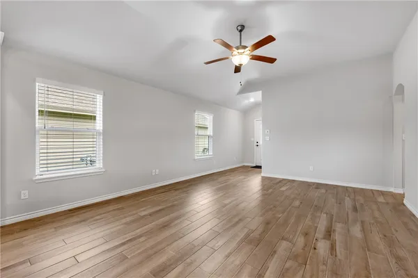 a view of an empty room with wooden floor and a window