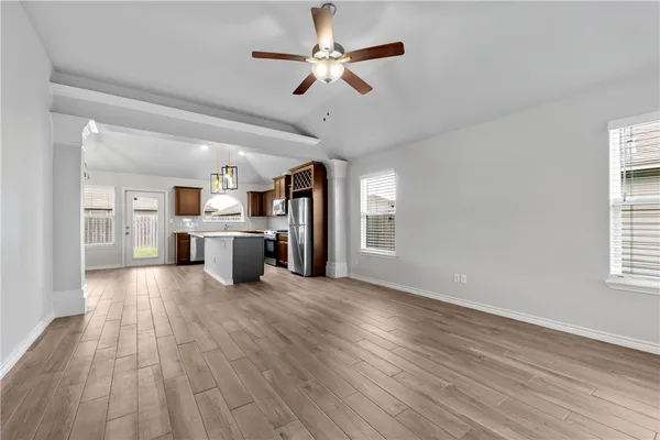 a large kitchen with stainless steel appliances granite countertop a stove oven a refrigerator with white cabinets and wooden floor