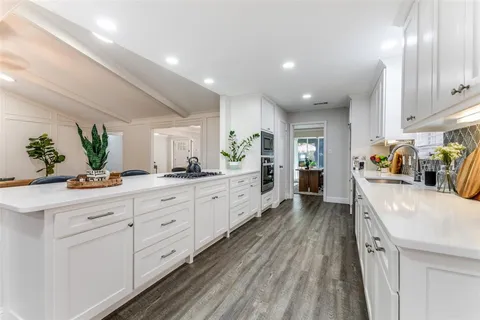 a large white kitchen with lots of counter space and wooden floor