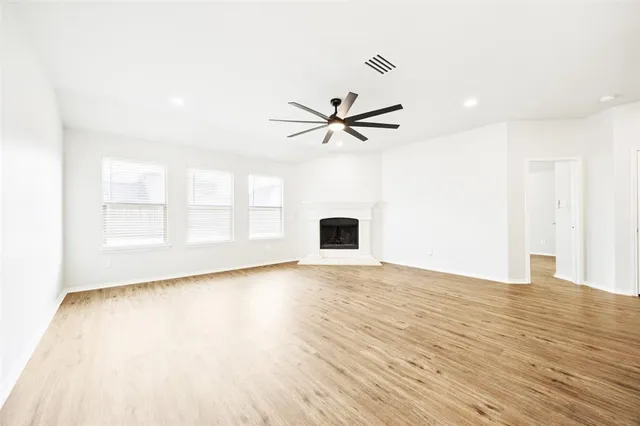 a view of an empty room with a window and wooden floor