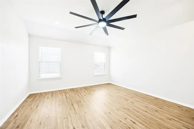 a view of empty room with wooden floor and fan
