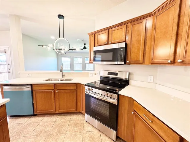 a kitchen with stainless steel appliances a sink a stove a microwave a sink a refrigerator and cabinets