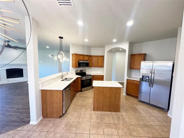 a kitchen with stainless steel appliances granite countertop a sink dishwasher a stove and a microwave with wooden floor