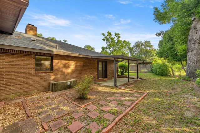 a view of a yard in front of a house with plants and large tree