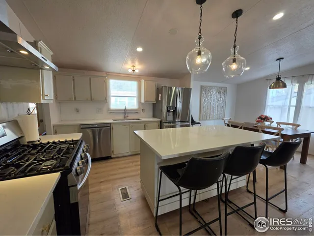 a kitchen with stainless steel appliances granite countertop a stove a sink a refrigerator a center island a stove and a cabinets