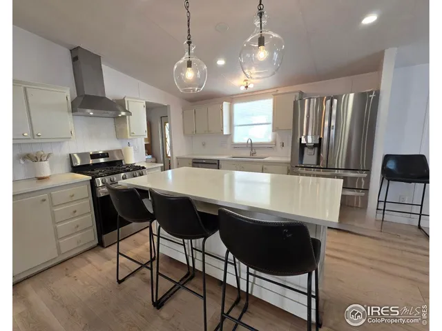 a kitchen with stainless steel appliances a dining table chairs and white cabinets