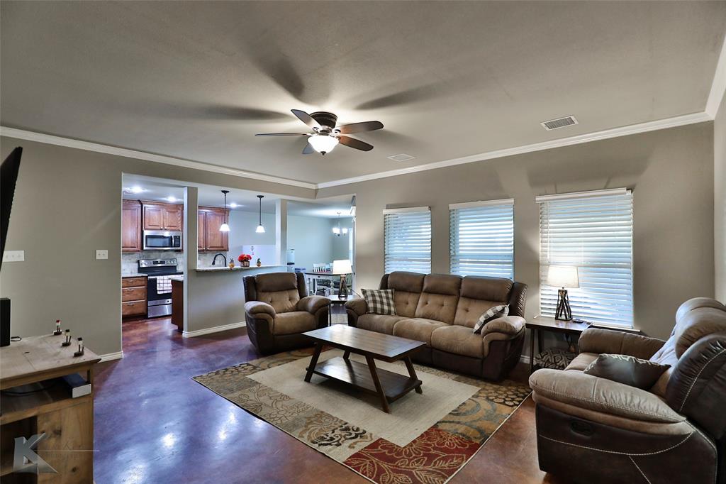 a living room with furniture a ceiling fan a lamp and a window