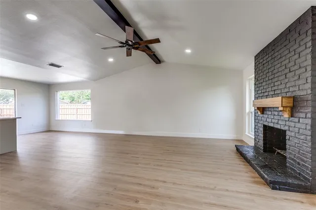 an empty room with windows and fireplace
