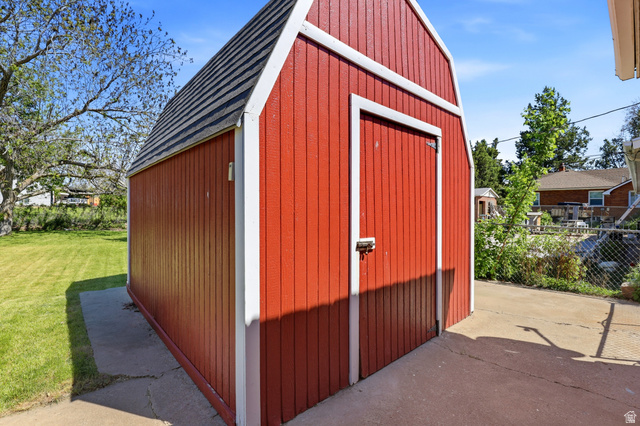 2348 North 770 West Clinton, UT 84015 - Photo 21 of 25 Red exterior storage shed with white trim, a single entry door, and a gambrel-style roof