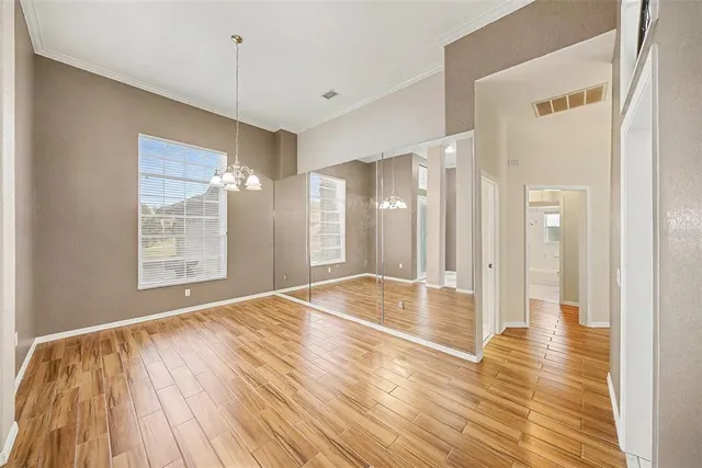a view of an empty room with wooden floor and a bathroom