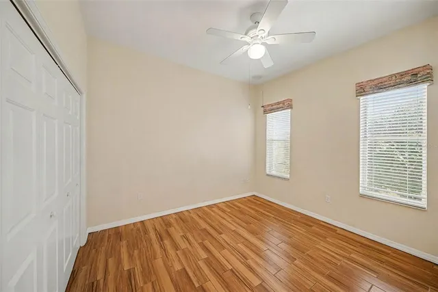 a view of empty room with wooden floor and fan
