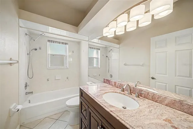 a bathroom with a granite countertop sink a toilet a mirror and shower