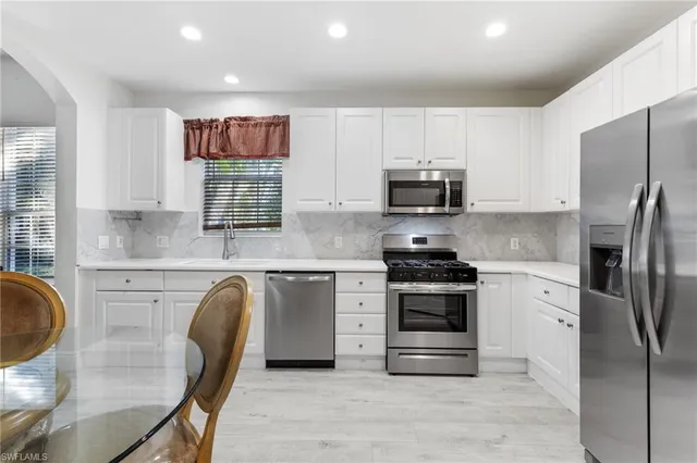 a kitchen with stainless steel appliances granite countertop a stove a refrigerator a microwave a sink and white cabinets