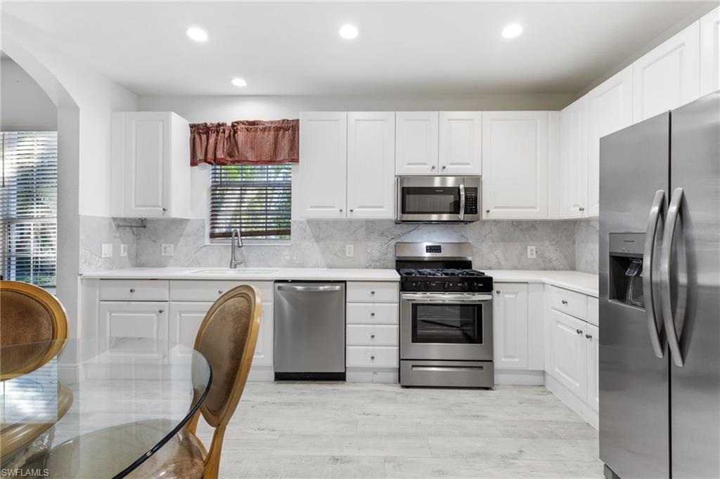 9079 Cascada Way, Unit 102 Naples, FL 34114 - Photo 17 of 49 a kitchen with stainless steel appliances granite countertop a stove a refrigerator a microwave a sink and white cabinets