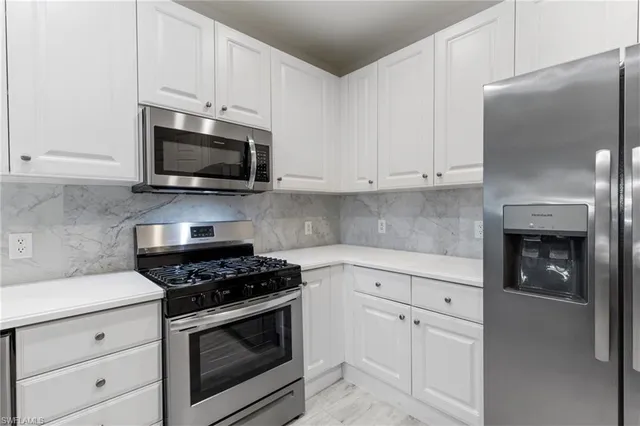 a kitchen with white cabinets and stainless steel appliances