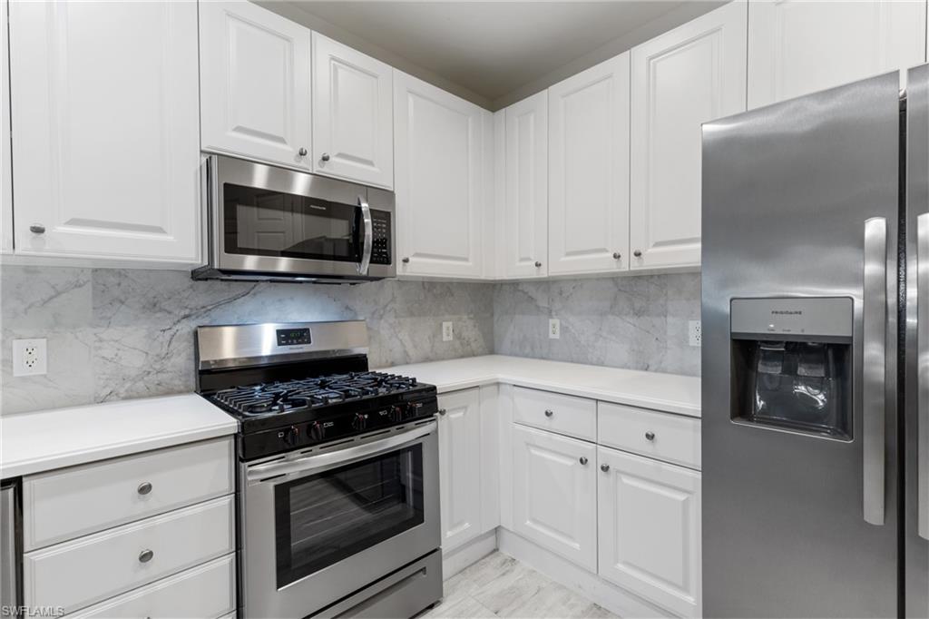 9079 Cascada Way, Unit 102 Naples, FL 34114 - Photo 19 of 49 a kitchen with white cabinets and stainless steel appliances