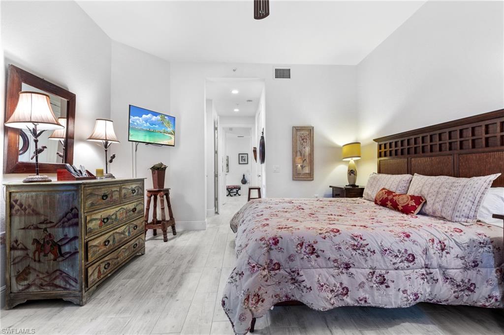 9079 Cascada Way, Unit 102 Naples, FL 34114 - Photo 24 of 49 a bedroom with a bed and wooden floor