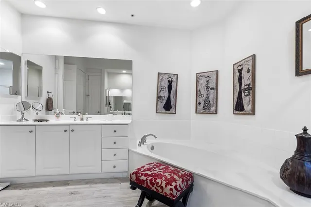 a spacious bathroom with double vanity sinks a mirror and a bathtub