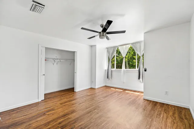 a view of an empty room with window and wooden floor